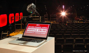 Bühnenansitz von DOKVILLE 2021 online mit Blick ins Kino. Man sieht einen Rechner und ein Mikro mit Plastikschutz (Foto: Günther Ahner / HDF)